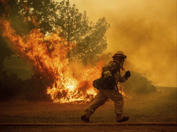 A firefighter runs while trying to save a home as a wildfire tears through Lakeport, Calif. on Tuesday, July 31, 2018.